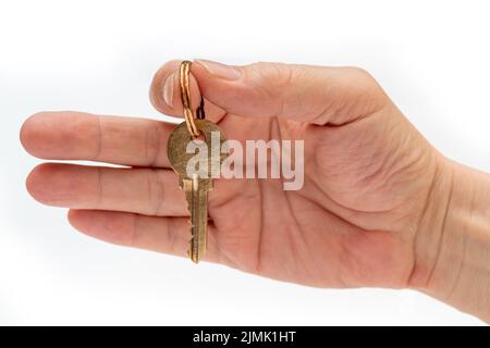 Chiave di appartamento in mano di un uomo. Chiave di bloccaggio porta in ottone. Foto Stock