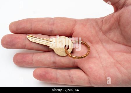 Chiave di appartamento in mano di un uomo. Chiave di bloccaggio porta in ottone. Foto Stock