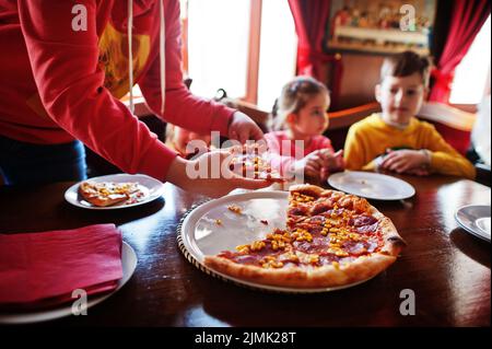 Bambini in compleanni seduti al tavolo e mangiando pizza. Foto Stock