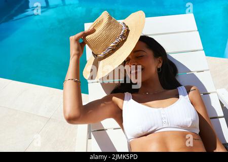 La vita è fresca a bordo piscina, una bella giovane donna che si rilassa su un lettino a bordo piscina. Foto Stock