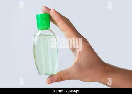 Mani con un piccolo flacone di disinfettante per le mani Foto Stock