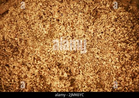 Trucioli di legno sono usati spesso per pacciamatura ed assestamento animale. Graniglia ad angolo elevato di trucioli di legno sul pavimento all'interno di un'officina di carpenteria. Foto Stock
