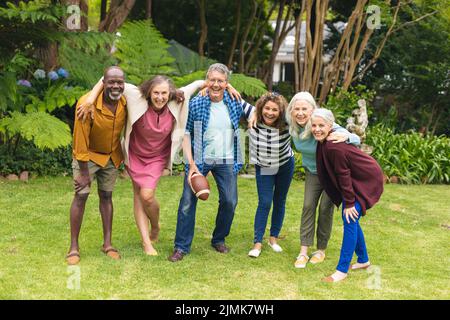 Ritratto di felice multirazziale senior maschile e femminile amici con le braccia intorno a giocare a rugby Foto Stock