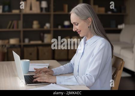 Felice anziano pensionato donna d'affari freelance che digita sul laptop Foto Stock