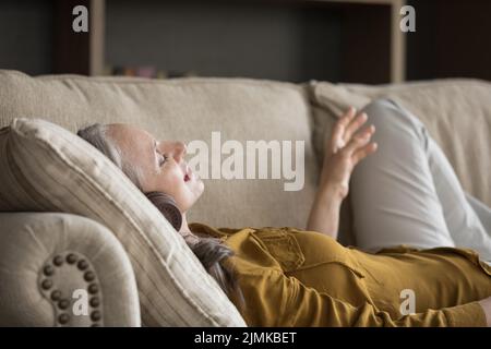 Donna adulta entusiasta che indossa cuffie moderne Foto Stock