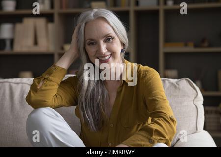 Felice gioiosa più vecchia 50s donna seduta sul divano a casa Foto Stock