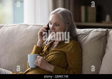 Bella donna di nonna in pensione grigio con capelli che parla sul telefono cellulare Foto Stock