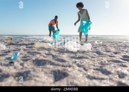 Vista a livello della superficie di coppia afro-americana raccolta rifiuti in spiaggia in giorno di sole Foto Stock