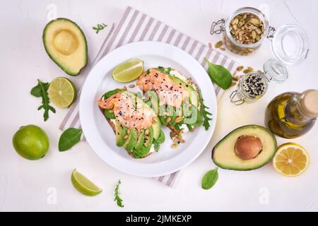 Avocado appena fatto, salmone e formaggio cremoso toast su un piatto di ceramica bianca Foto Stock