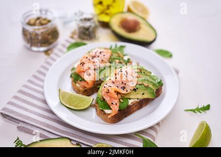 Avocado appena fatto, salmone e formaggio cremoso toast su un piatto di ceramica bianca Foto Stock