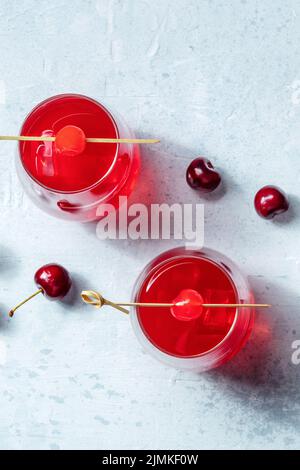 Ciliegia da cocktail e coda di mock, una vivace bevanda rossa con ghiaccio Foto Stock