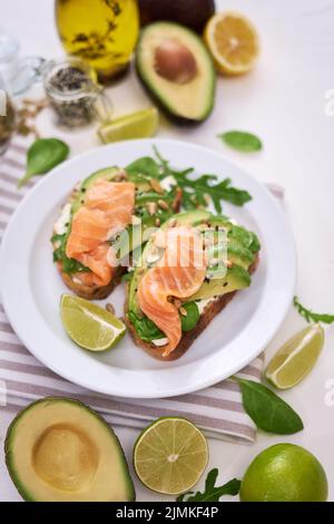 Avocado appena fatto, salmone e formaggio cremoso toast su un piatto di ceramica bianca Foto Stock