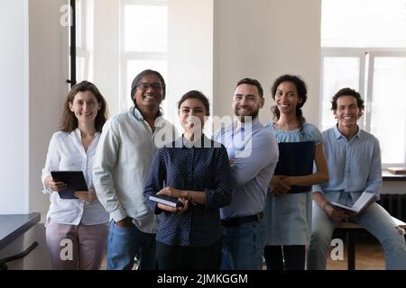 Gruppo di dipendenti aziendali soddisfatti e diversificati che si pongono sul posto di lavoro Foto Stock