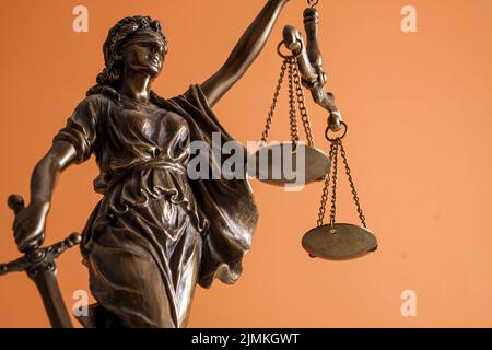 Statua di Themis la dea della giustizia come simbolo della libertà di protezione e del diritto. Vista Hero su sfondo arancione luminoso. Foto Stock