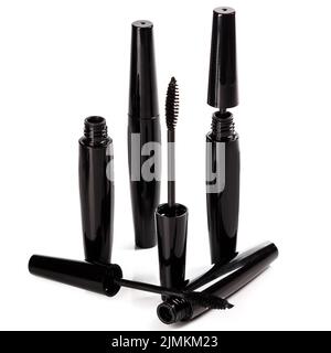 Spazzole e contenitori in mascara nero su sfondo bianco Foto Stock