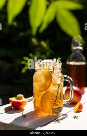 Tè freddo con pesche in un bicchiere Foto Stock