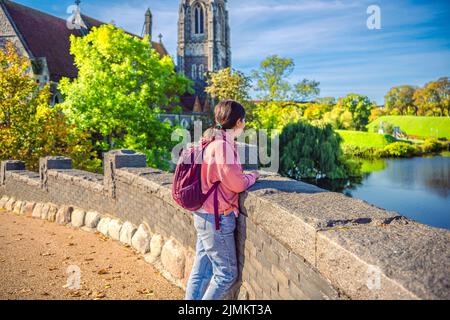 Una ragazza dai capelli neri guarda l'acqua nel lago vicino alla chiesa di San Albans. Copenaghen, Danimarca Foto Stock