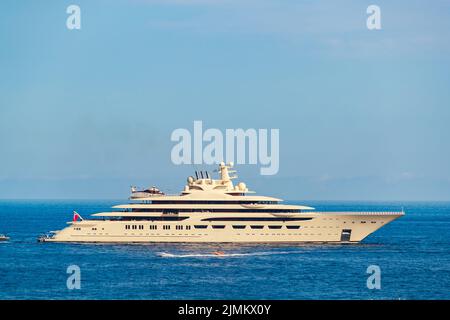 L'enorme mega yacht beige è ormeggiato in mare nelle giornate di sole, il corrimano cromato, riflesso del sole su bordo lucido del motore Foto Stock