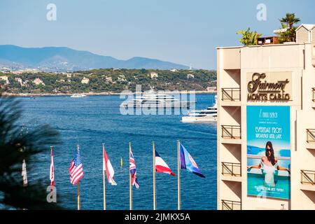 Monaco, Monte Carlo, 21 agosto 2017: L'hotel Fairmont, bandiere di diversi paesi su palchi, mega yacht sullo sfondo, M Foto Stock