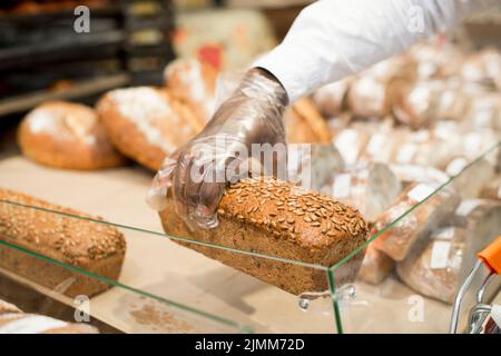 Mano che tiene il pane sfondo sfocato Foto Stock