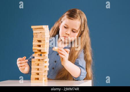 Ragazza carina che rimuove i blocchi dalla torre jenga Foto Stock