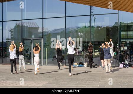 Giovani adulti o adolescenti che praticano la danza si muovono di fronte alla biblioteca di Oodi a Helsinki, Finlandia Foto Stock