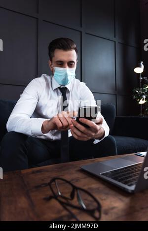 Uomo d'affari che indossa maschera di prevenzione durante il suo lavoro in un ufficio Foto Stock