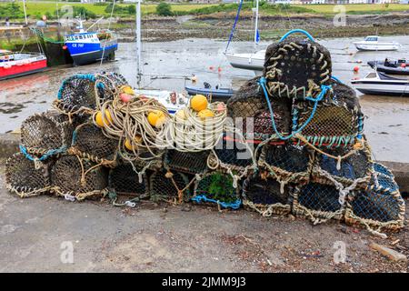 L'isola di Whithorn, Scozia - 13 giugno 2022: Vasi di aragosta, Galleggianti e funi accatastati sulla parete del porto con il porto sullo sfondo basso Foto Stock