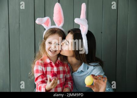 Madre coniglietto orecchie baciare la guancia figlia Foto Stock