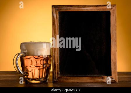 Lavagna vuota con tavolo in legno di birra di vetro Foto Stock