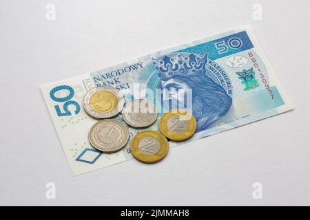 Banconote e monete polacche da cinquanta zloty in primo piano su bianco Foto Stock