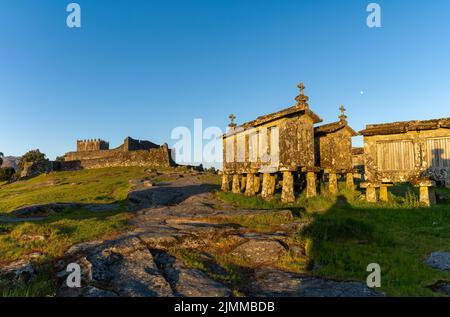 Il castello di Lindoso e i granai storici in pietra nel villaggio di Lindoso in Portogallo in calda luce serale Foto Stock