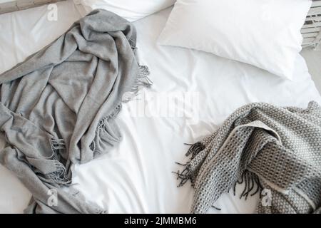 Letto non fatto con cuscini e coperte grigie vista dall'alto Foto Stock