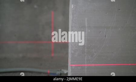 Livella laser illuminata. Pavimento a livello laser. Livellamento della parete con una livella laser.Visualizza linee perpendicolari. Laser sulle pareti in preparazione al lev Foto Stock