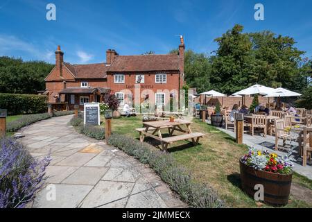 Il pub in bottiglia di pelle a Mattingley, Hampshire, Inghilterra, Regno Unito, un vecchio villaggio inn, con persone che godono di bevande nella birreria all'aperto in una giornata estiva Foto Stock