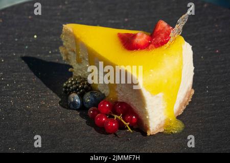 Deliziosa cheesecake con frutti di bosco su un piatto nero in un ristorante Foto Stock