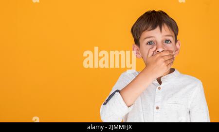 Bambino che copre la bocca con spazio copia Foto Stock