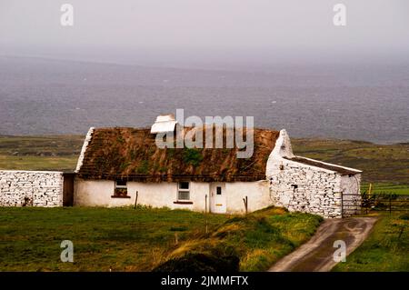 Cottage con tetto in paglia ai margini del Burren in Irlanda. Foto Stock