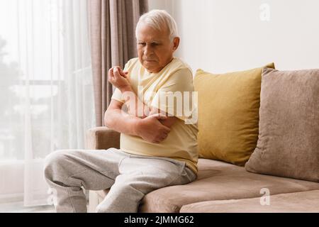 Uomo anziano che soffre di dolore al gomito Foto Stock