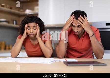 Sconvolto disperato moglie e marito afroamericano millennial nella stessa t-shirt pensare e lavorare con i documenti Foto Stock