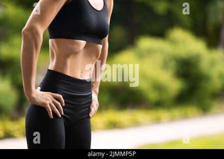 Una donna sportiva irriconoscibile che si alletta all'aperto, facendo esercizio di fitness ventre vuoto Foto Stock