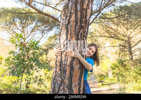 Giovane donna che abbraccia la foresta di alberi Foto Stock