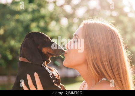 Vista laterale bella giovane donna baciare il suo cane Foto Stock