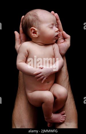 Cute neonato bambino giacente nelle mani del padre Foto Stock