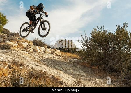 Motociclista professionista che salta durante la discesa in bicicletta Foto Stock