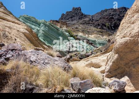 Turchesi strato di roccia los Azulejos De Veneguera, roccia vulcanica intrisa di sodio silicato di ferro, a Mogan, lampreda di erba Foto Stock