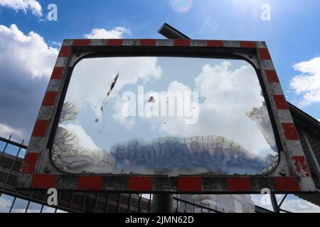Un vecchio specchio di sicurezza resistente alle intemperie su una strada Foto Stock