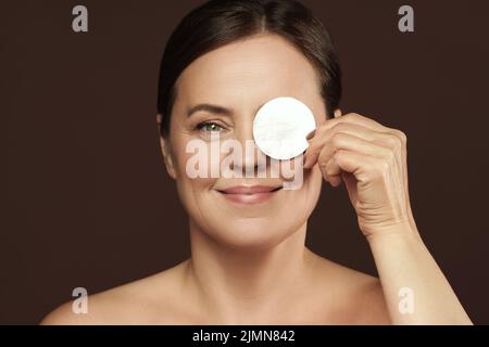 Bella donna di mezza età con un tampone di cotone per la pulizia del viso o la routine di rimozione del make-up Foto Stock