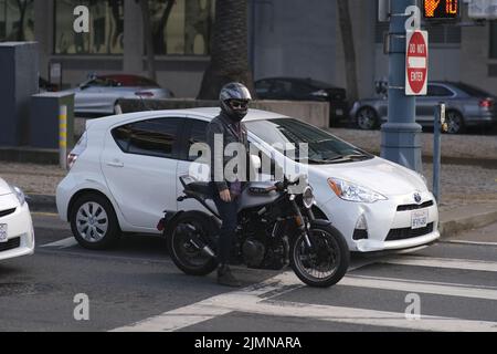 Un giovane motociclista maschio in un casco in attesa al semaforo di San Francisco Foto Stock