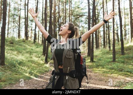 Giovane escursionista femminile con grande zaino in verde foresta Foto Stock